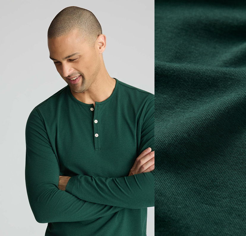 Man wearing a green long-sleeve shirt, smiling and looking down.