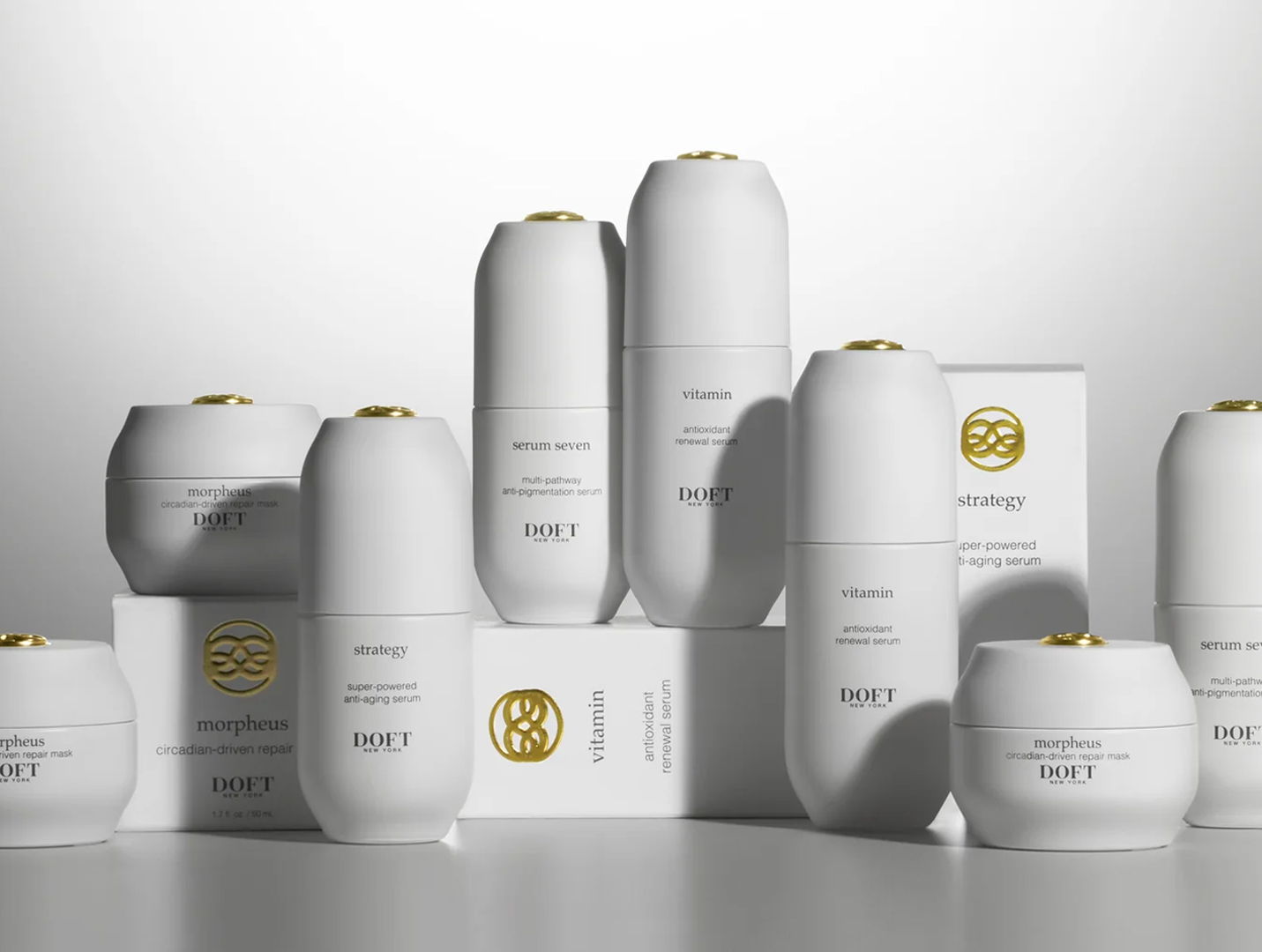 A collection of white skincare bottles and boxes with gold accents.