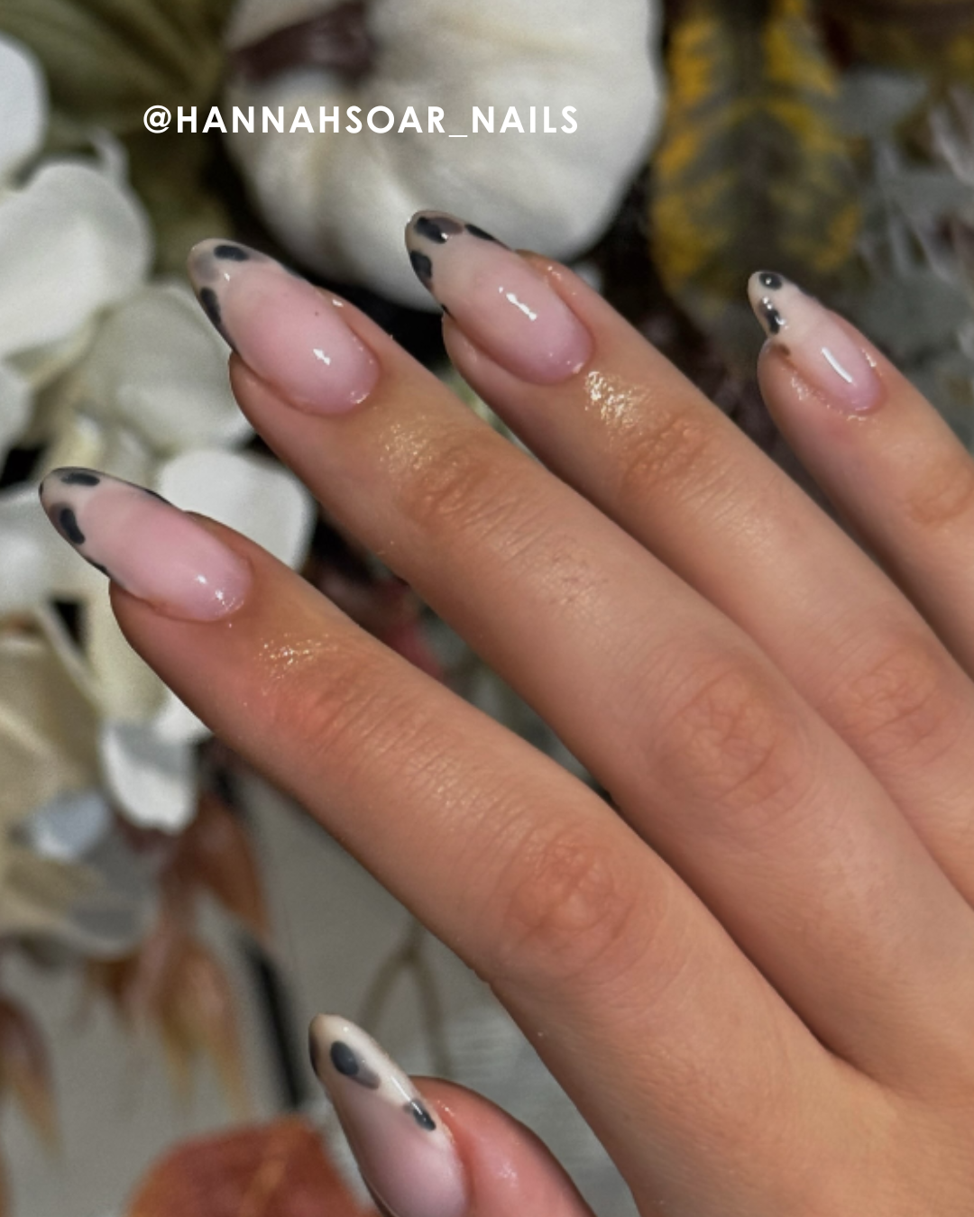 A hand with stylish pink and black nails among decorative elements.