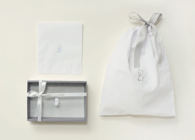 Gift packaging with a card and a white fabric bag.