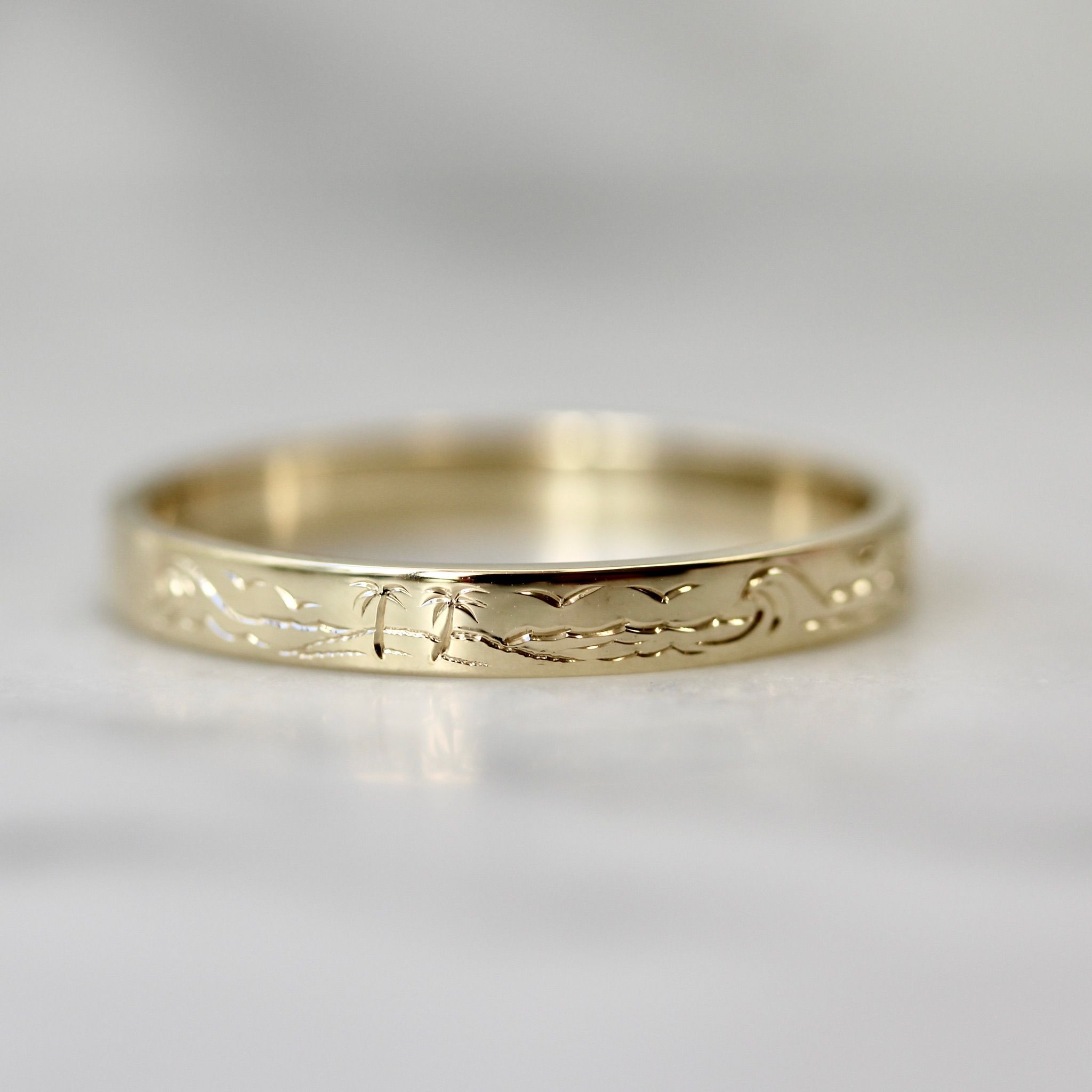 Hand-engraved wedding band with ocean waves, palm trees, and birds