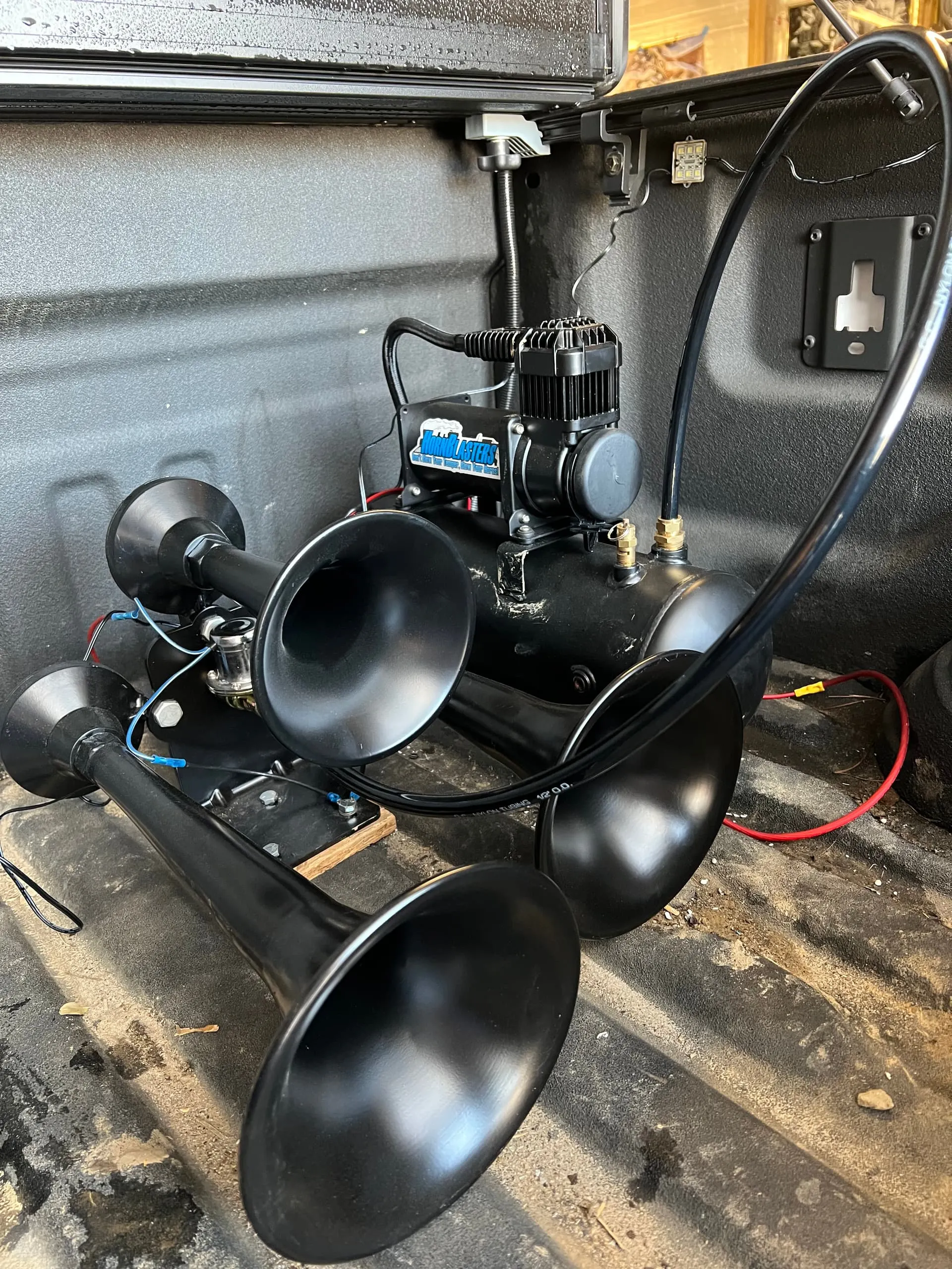 HornBlasters train horn kit with four black trumpets, compressor, and air tank mounted in Jimmy's truck bed
