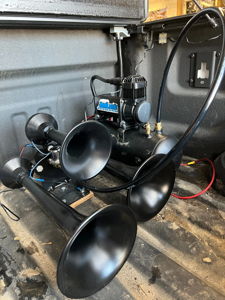 HornBlasters train horn kit with four black trumpets, compressor, and air tank mounted in Jimmy's truck bed