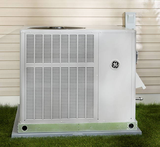 Image of GE Residential HVAC AC Only Package Unit, installed outside of a home, facing front