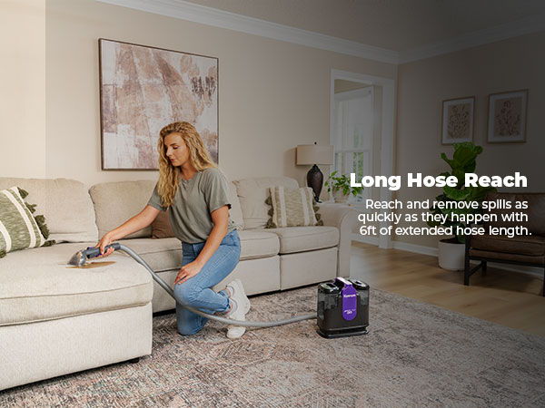 Person spot cleaning a couch with a long hose reach