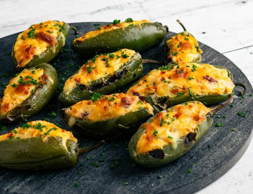 Stuffed jalapeños on a black serving platter.