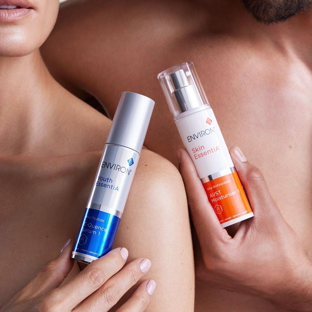 Two hands holding one Environ product each. First hand is holding Environ Youth EssentiA and second hand is holding Environ Skin EssentiA AVST Moisturiser