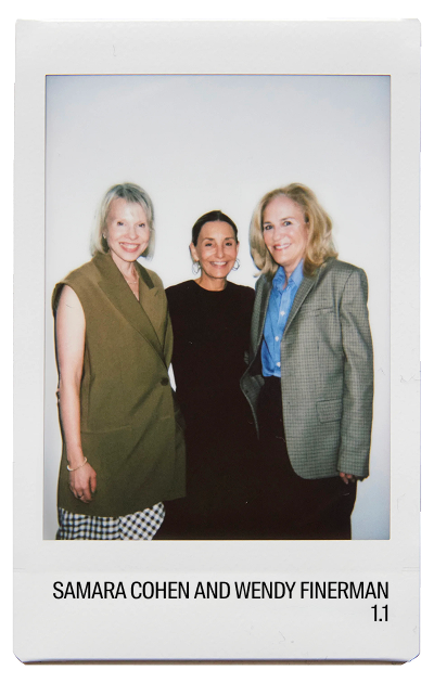 Three women posing for a photo, smiling against a plain background.