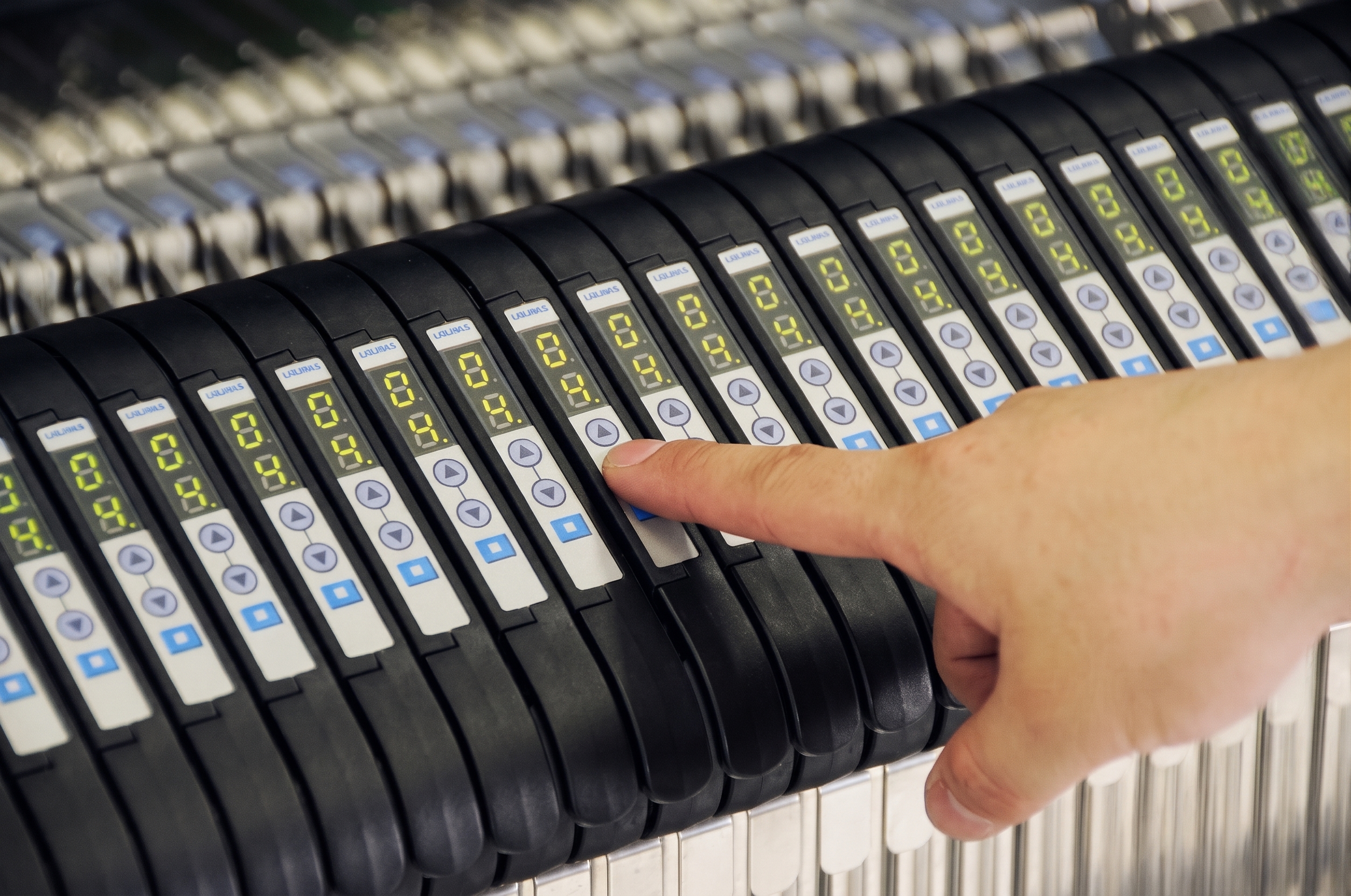 A hand pointing at numbered black disks on a machine.
