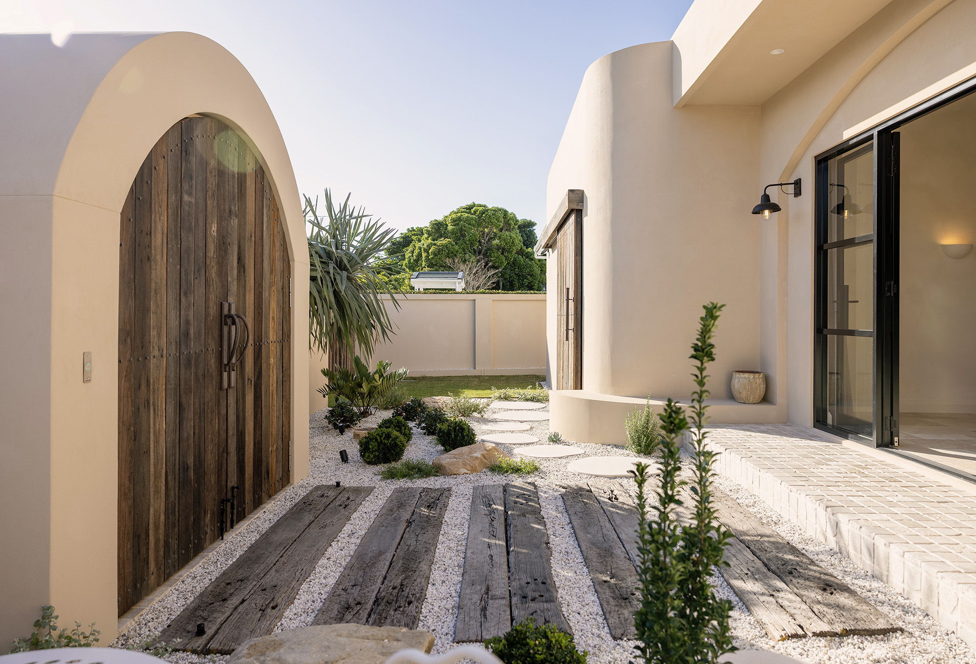 A modern entrance with a wooden door and landscaped pathway.