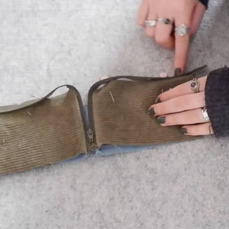 hand showing how to sew the zipper to the fabric pieces to make a wallet