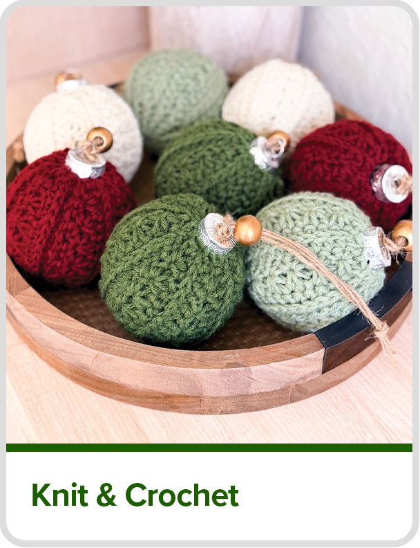 Colorful knitted ornaments arranged in a wooden bowl.