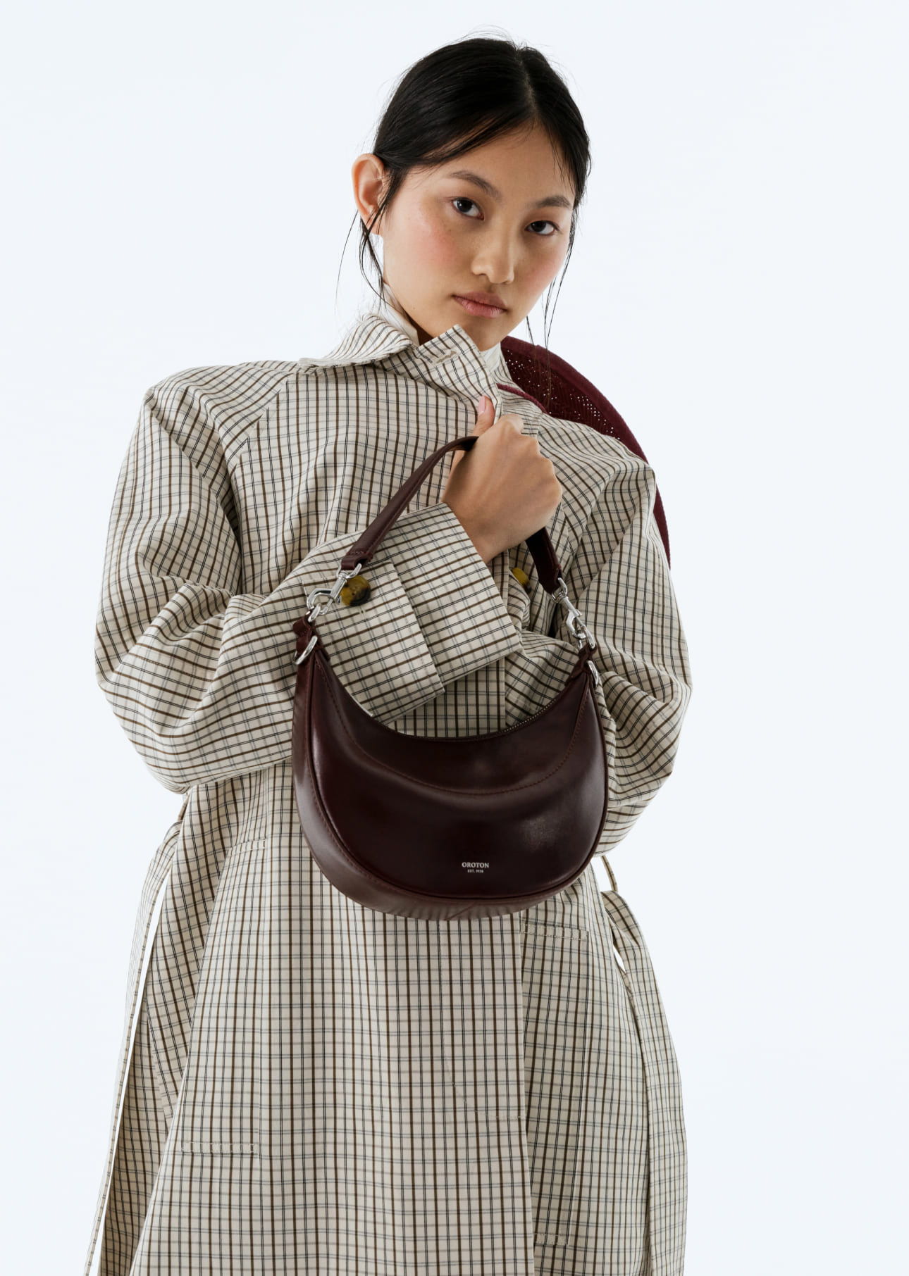 Young woman in a patterned coat holding a handbag.