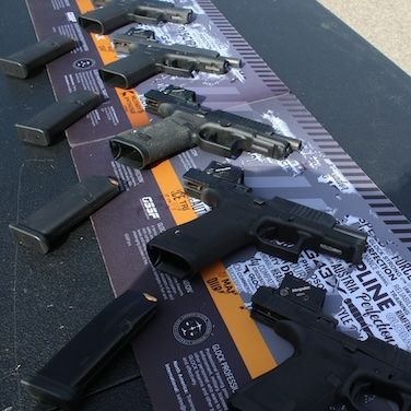 A row of handguns displayed on a table with information sheets.