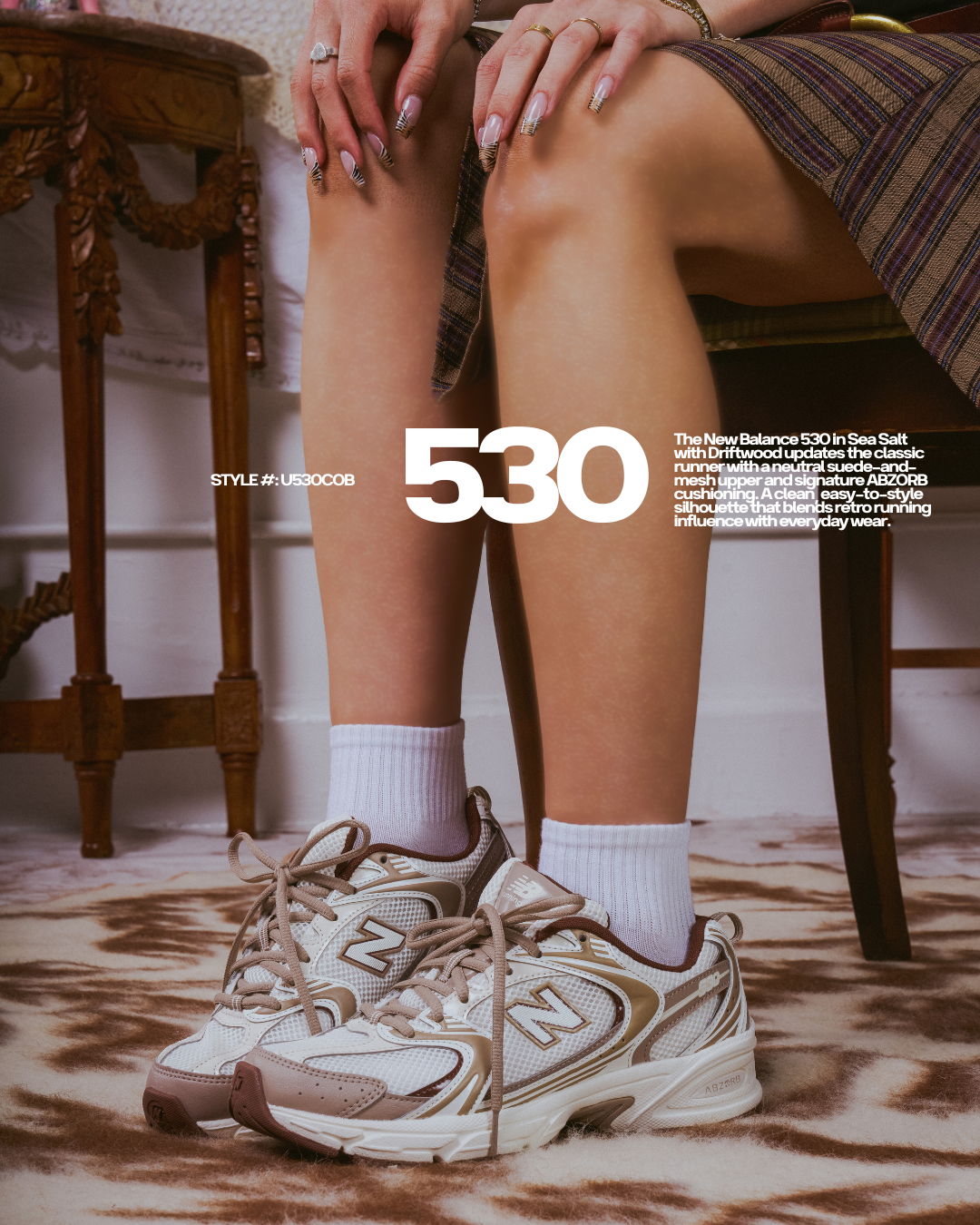 Person sitting with New Balance 530 sneakers and white socks, legs crossed.