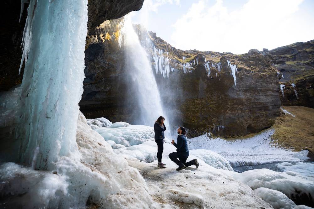 couple proposing underneath waterfall in iceland