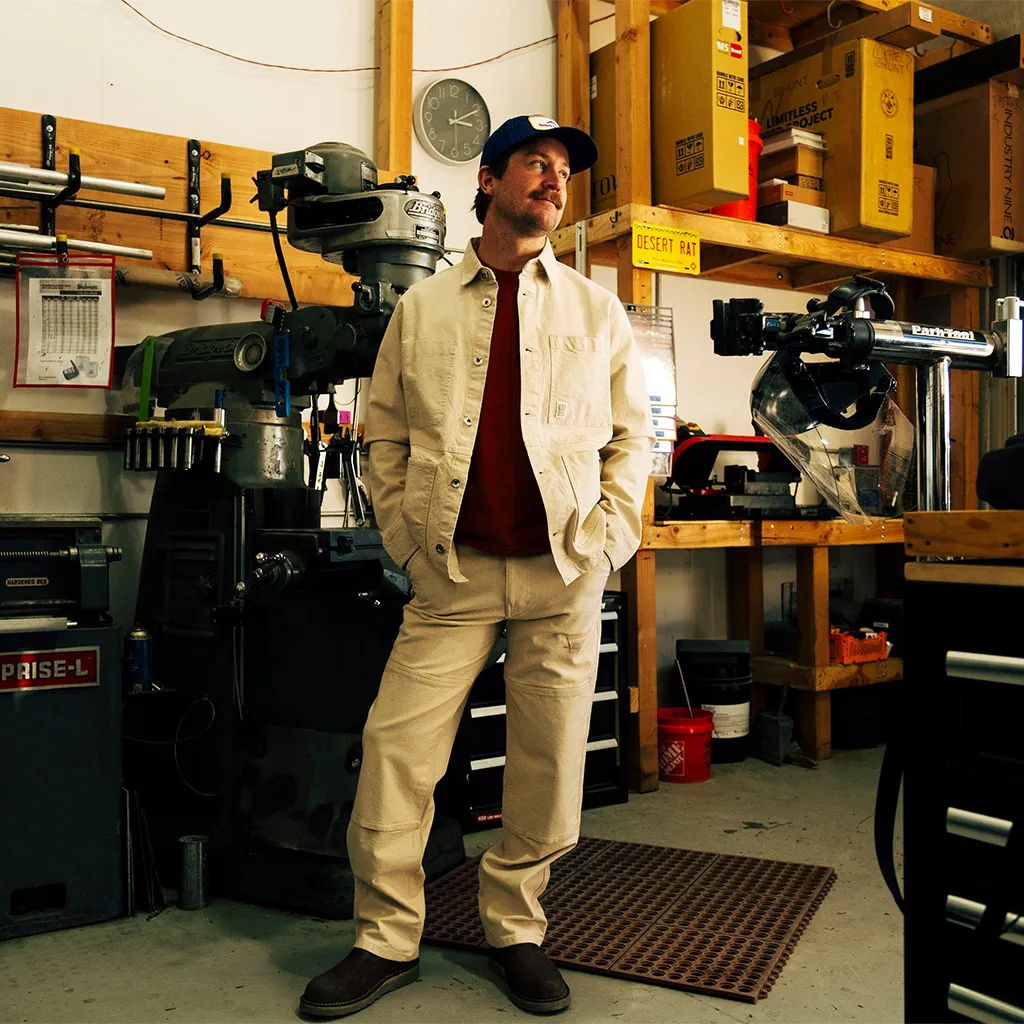 Person standing in a workshop with tools and machinery in the background.