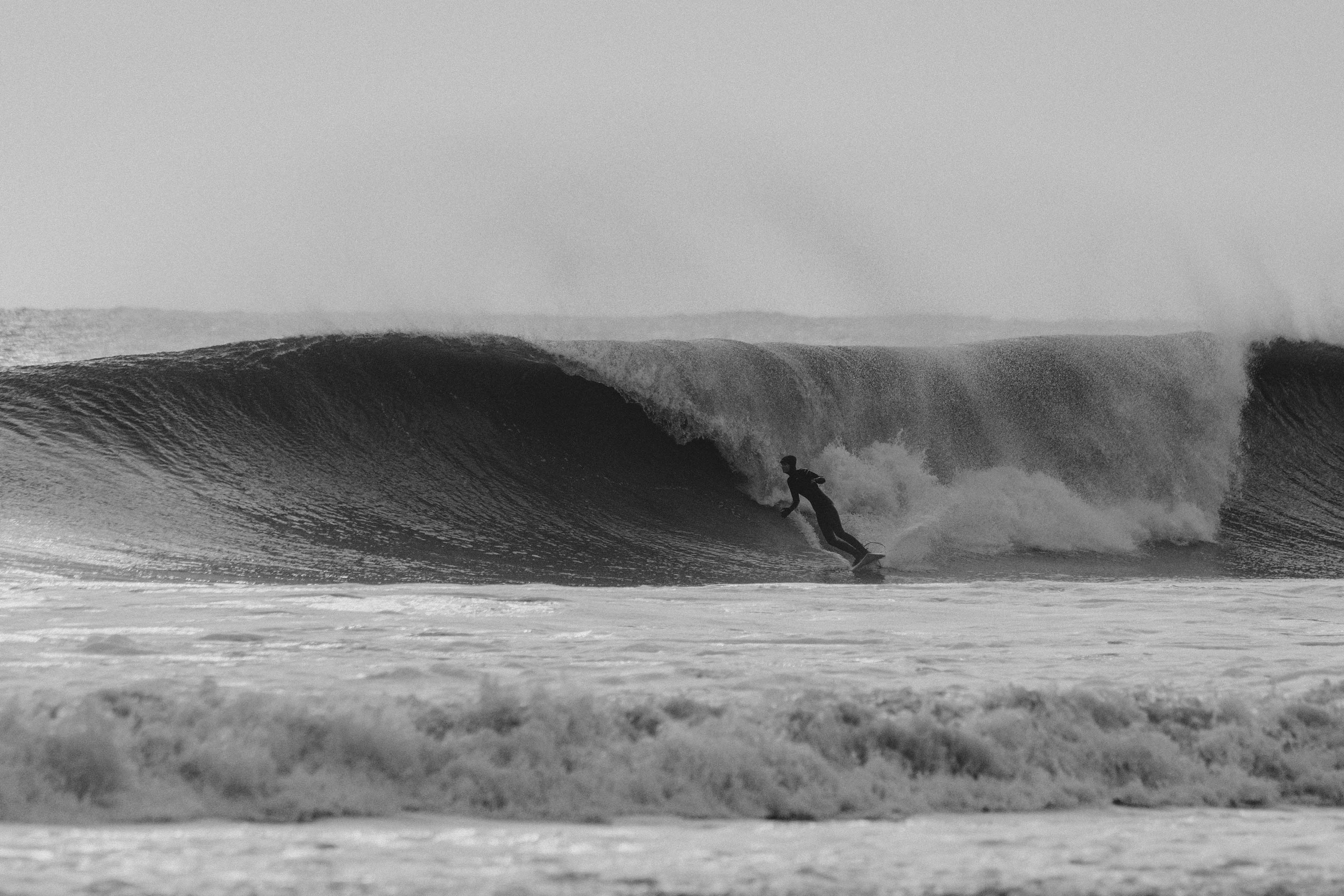 Surfer riding a large wave in black and white.