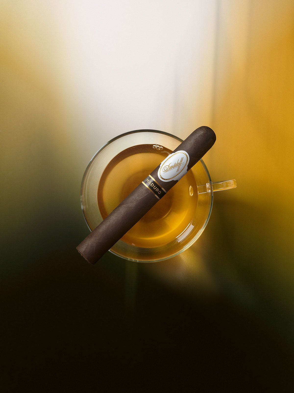 Eine Davidoff Maduro-Zigarre, die auf einem Glas liegt, das mit Lapsang-Souchong-Tee gefüllt ist.