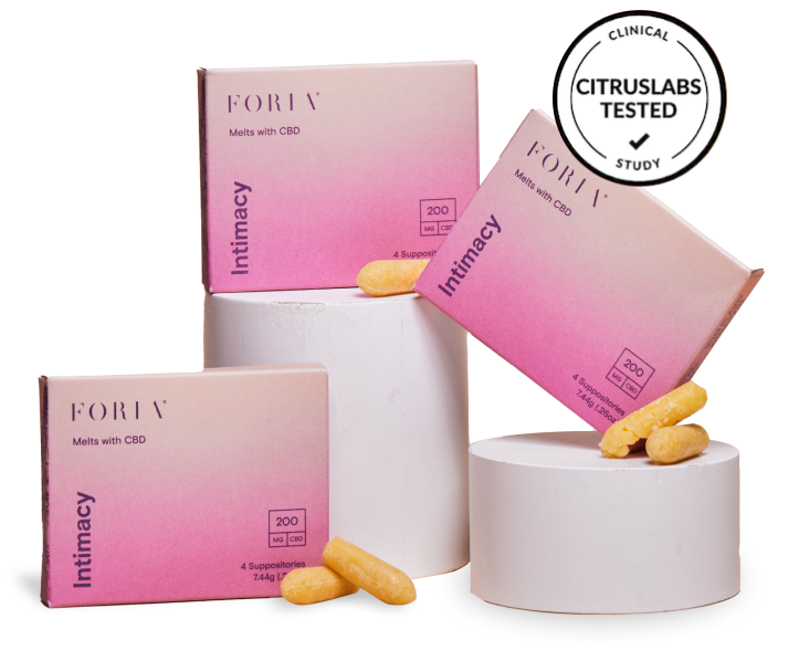 Three boxes of Foria Intimacy Melts with pink packaging design, two of them on short cylindar display pillars, and loose melts resting against one of the boxes, plus a “Citruslabs Tested Clinical Study” badge to indicate the product’s quality and efficacy.