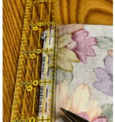 Close-up of using a ruler and a heat erasable marking pen to draw a 3/8-inch seam allowance on the placemat backing fabric