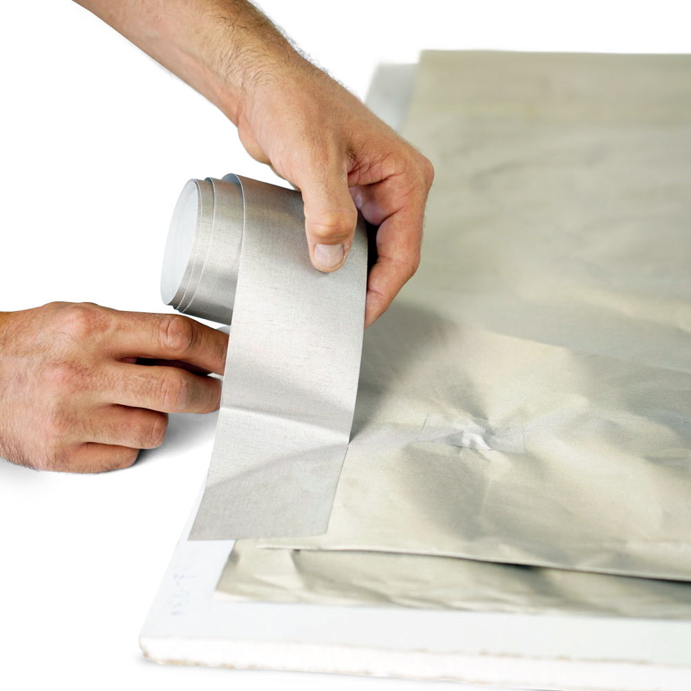 Hands applying a strip of TitanRF Faraday Tape along the seam of a sheet of TitanRF Faraday Fabric.