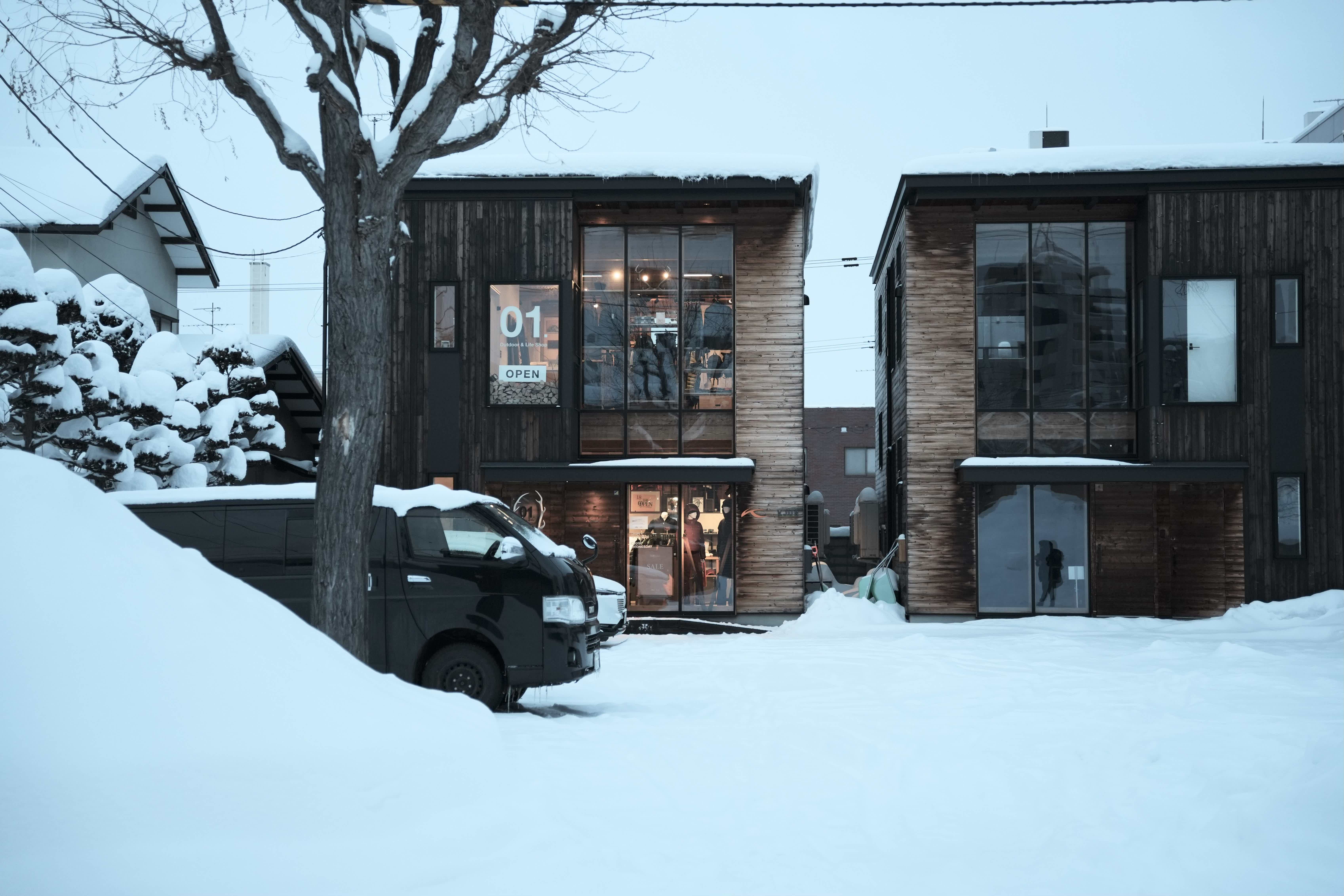 Two modern wooden houses covered in snow.