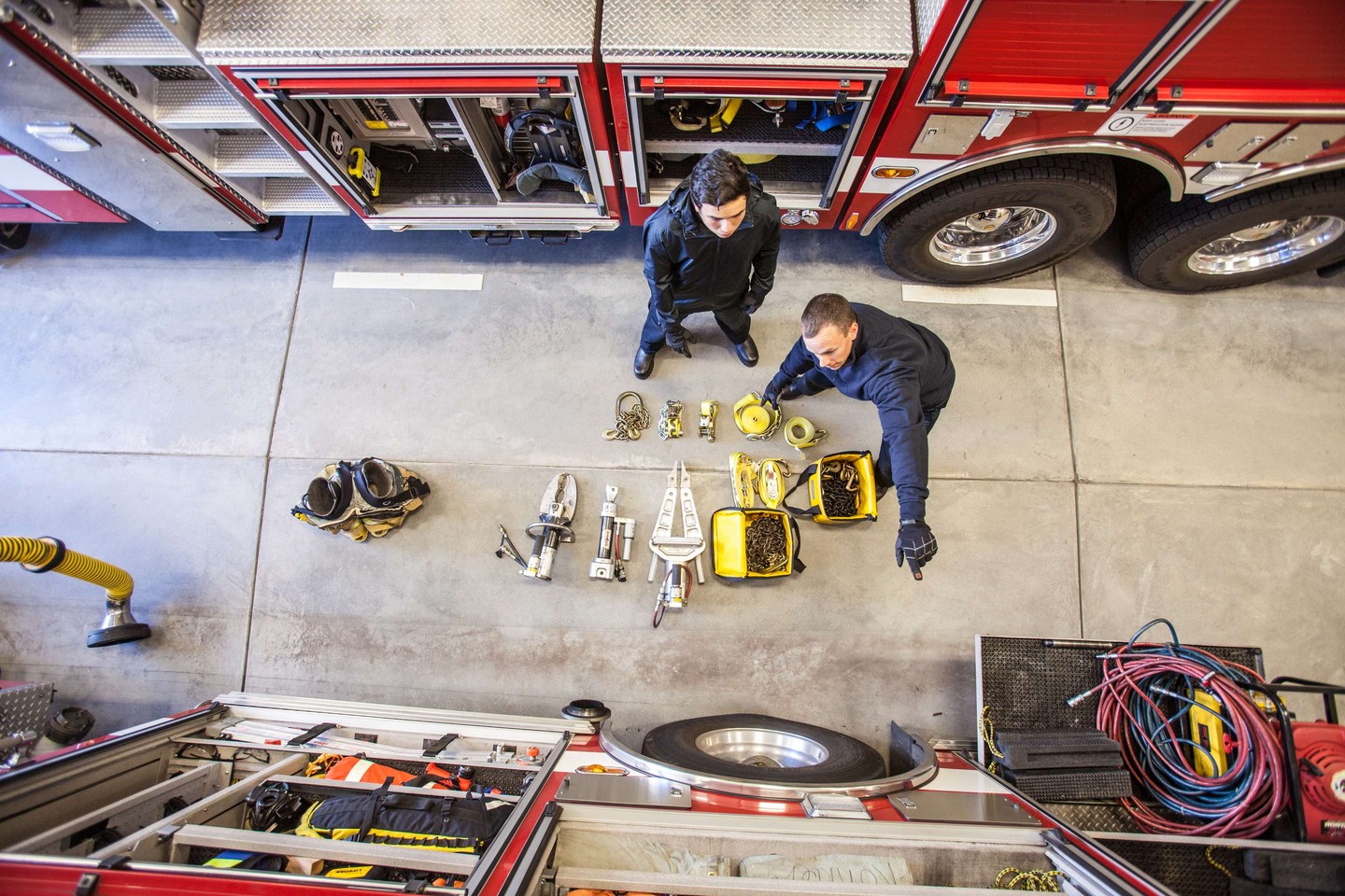 Two firefighters inspecting equipment in a fire station.