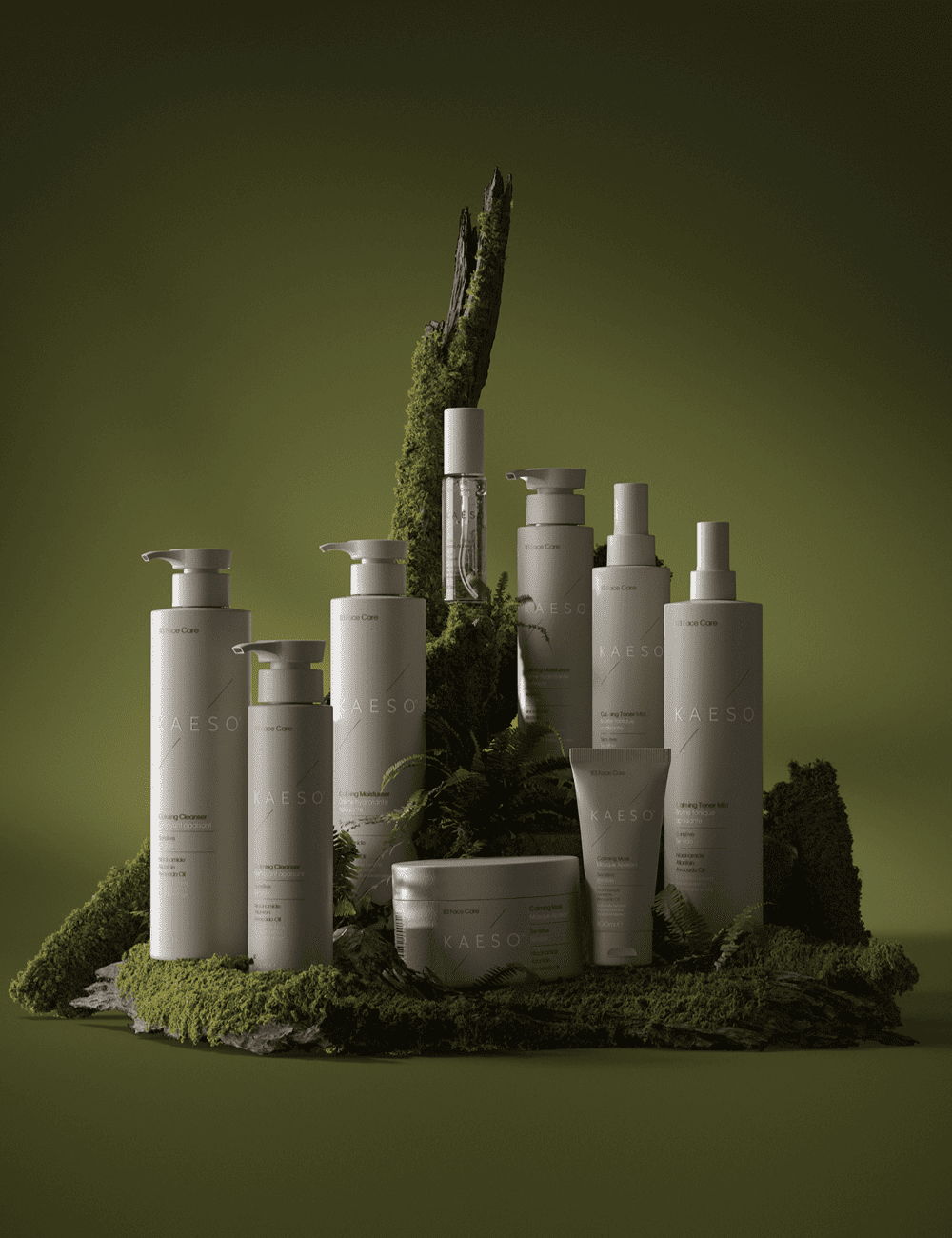 Collection of skincare products arranged on mossy surface against green background.
