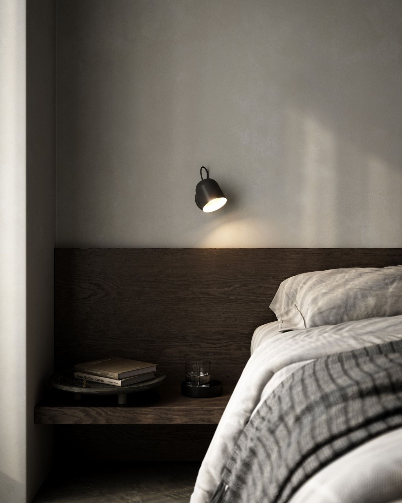 Modern bedroom with a bed, nightstand, and black wall-mounted adjustable light fixture.