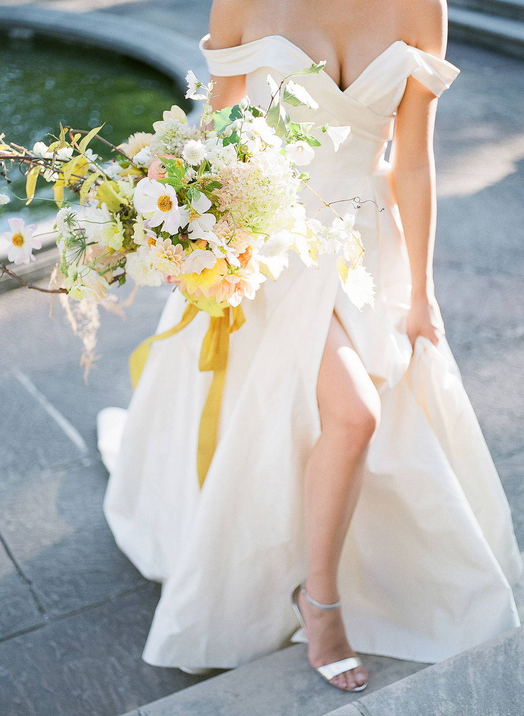 bride holding a yellow, white and peach floral bouquet 