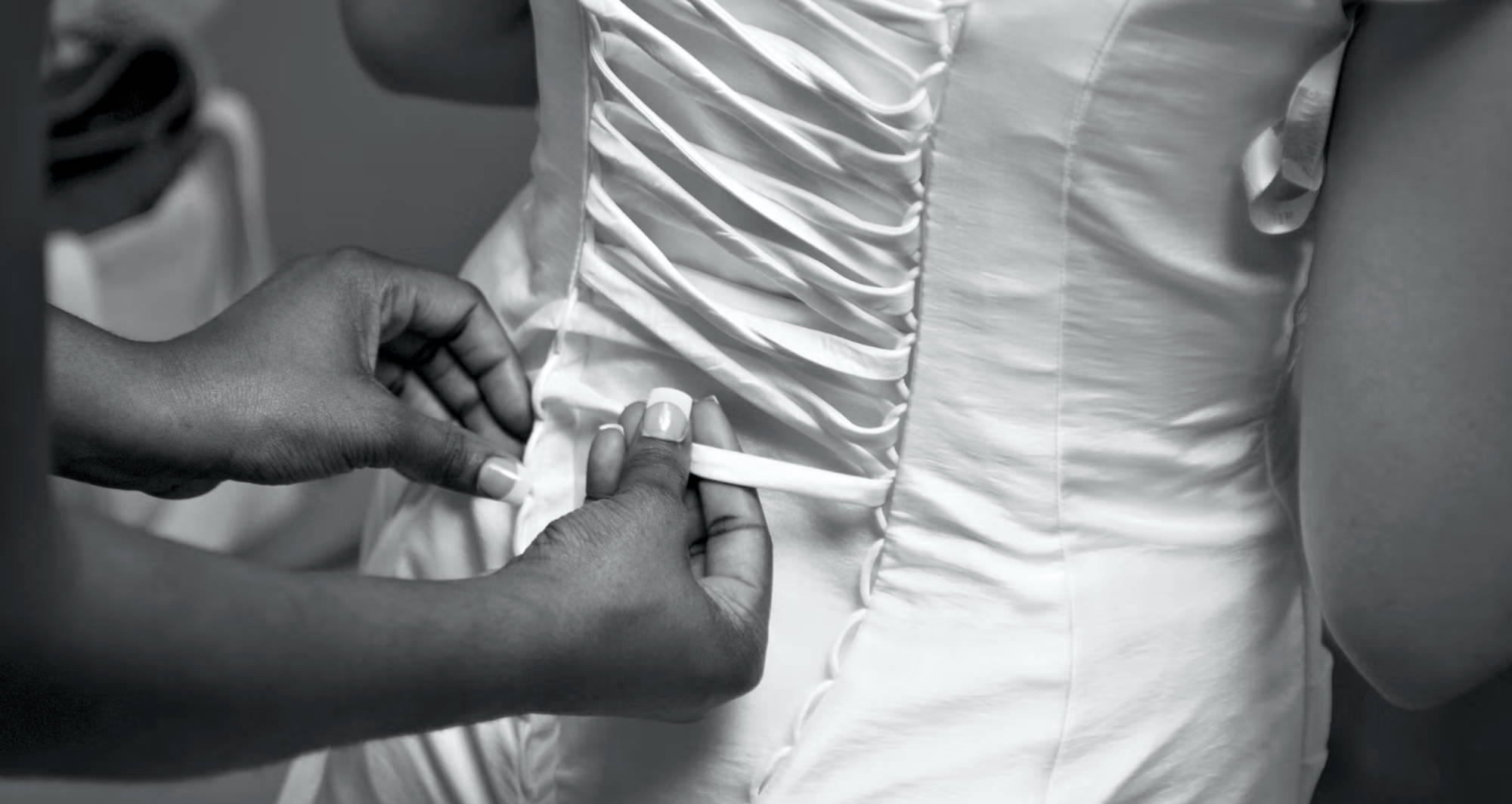 a white corset being laced up by a pair of hands