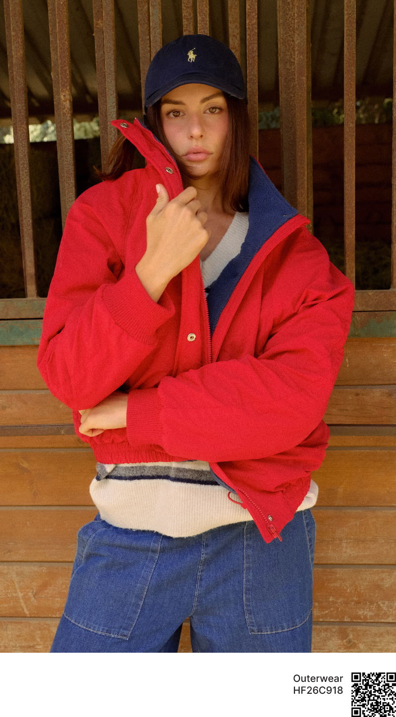 Person in red jacket and cap posing against wooden background.