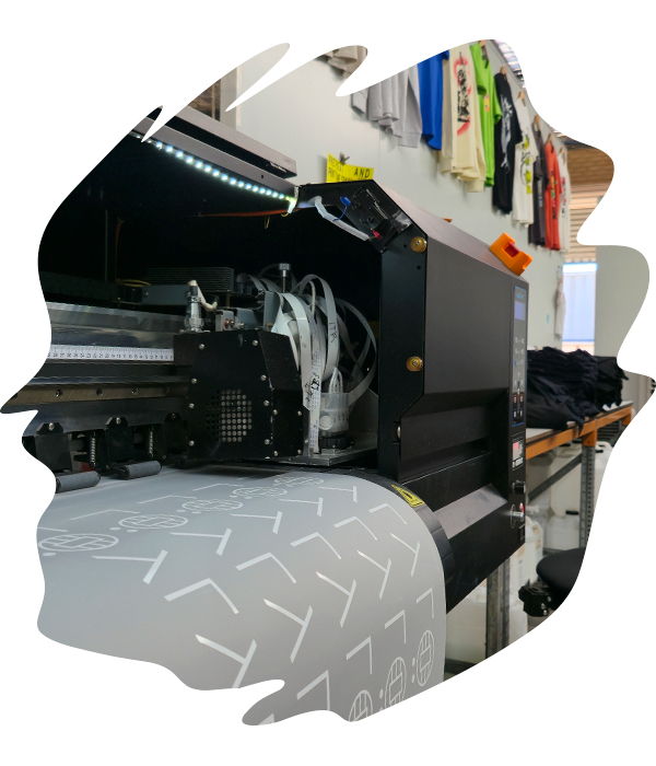 Close-up of a large industrial DTF printer actively printing white ink transfers onto clear PET film