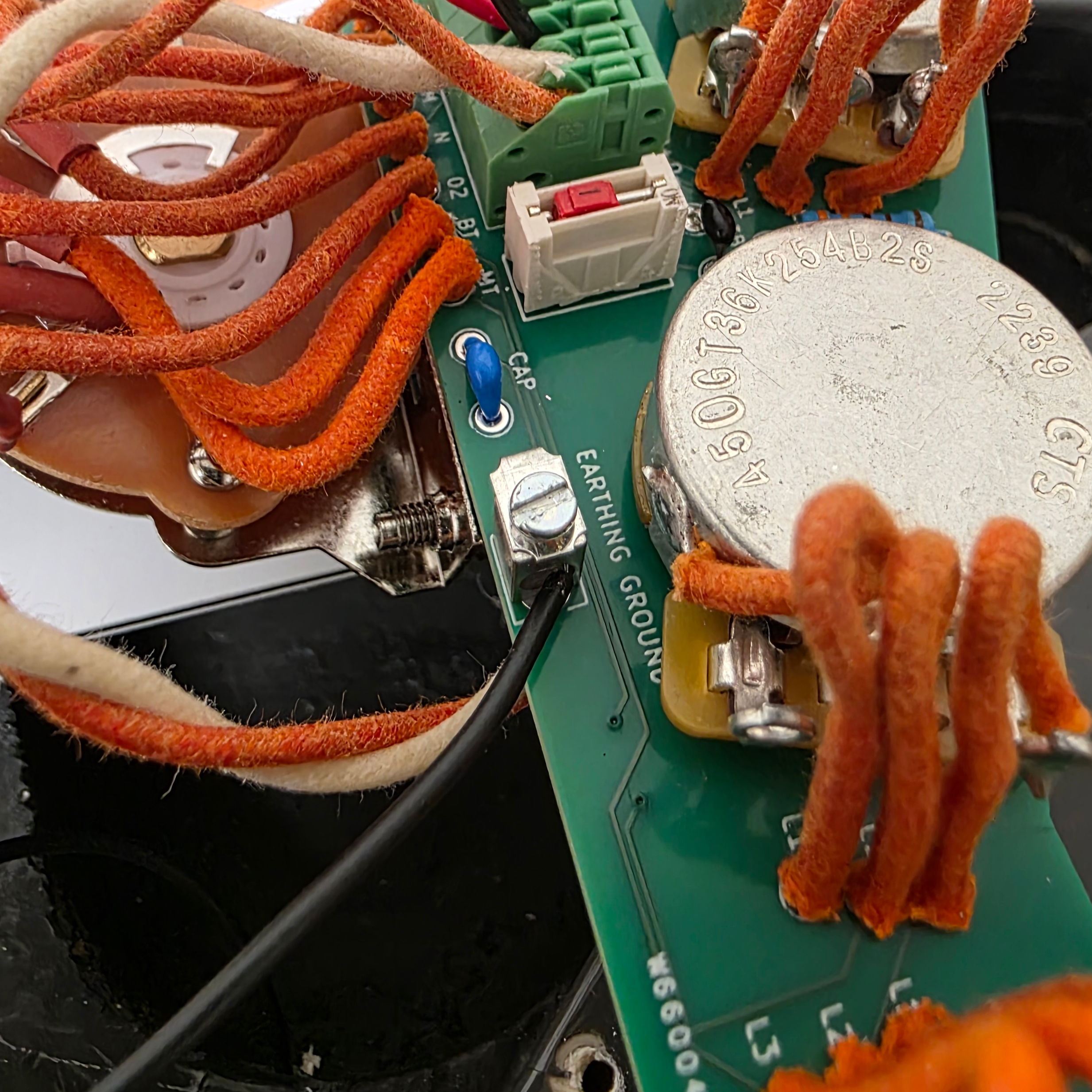 Close-up of a circuit board with orange wires and electronic components.