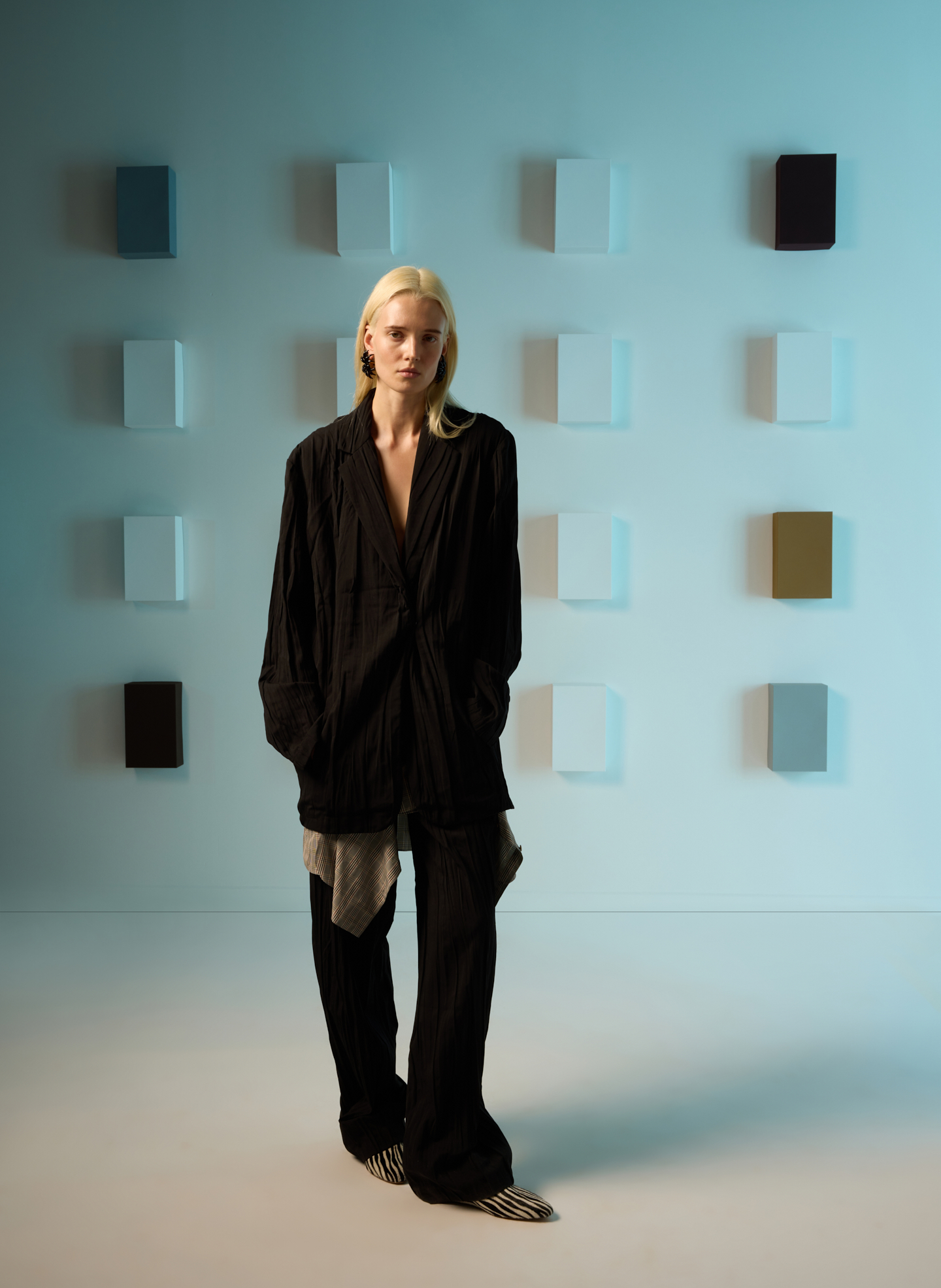 Model in black outfit standing against a wall of color samples.