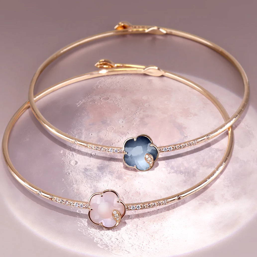 Two gold bangles with floral designs featuring colorful stones.