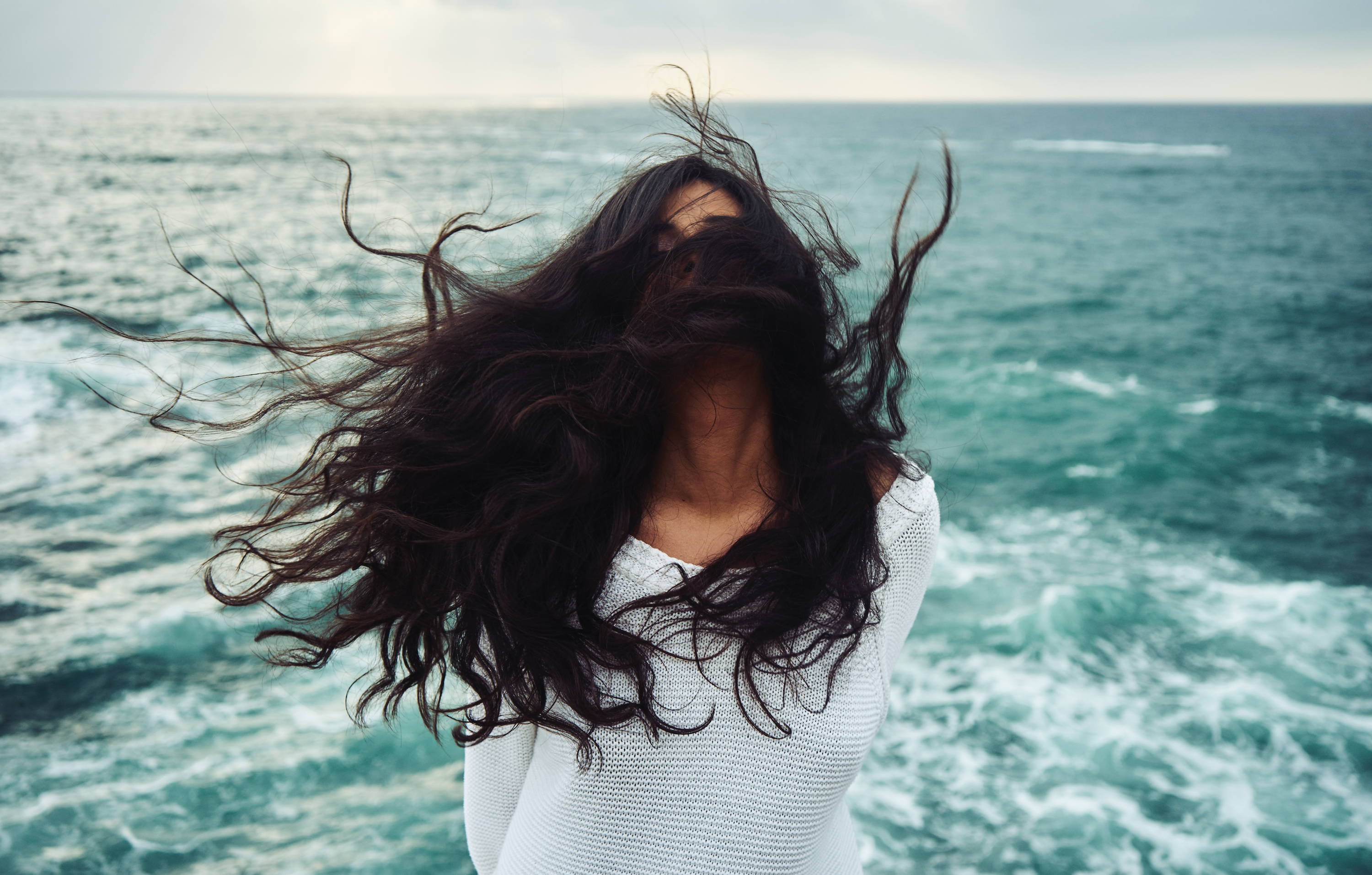 cabello salvaje con el océano en el fondo