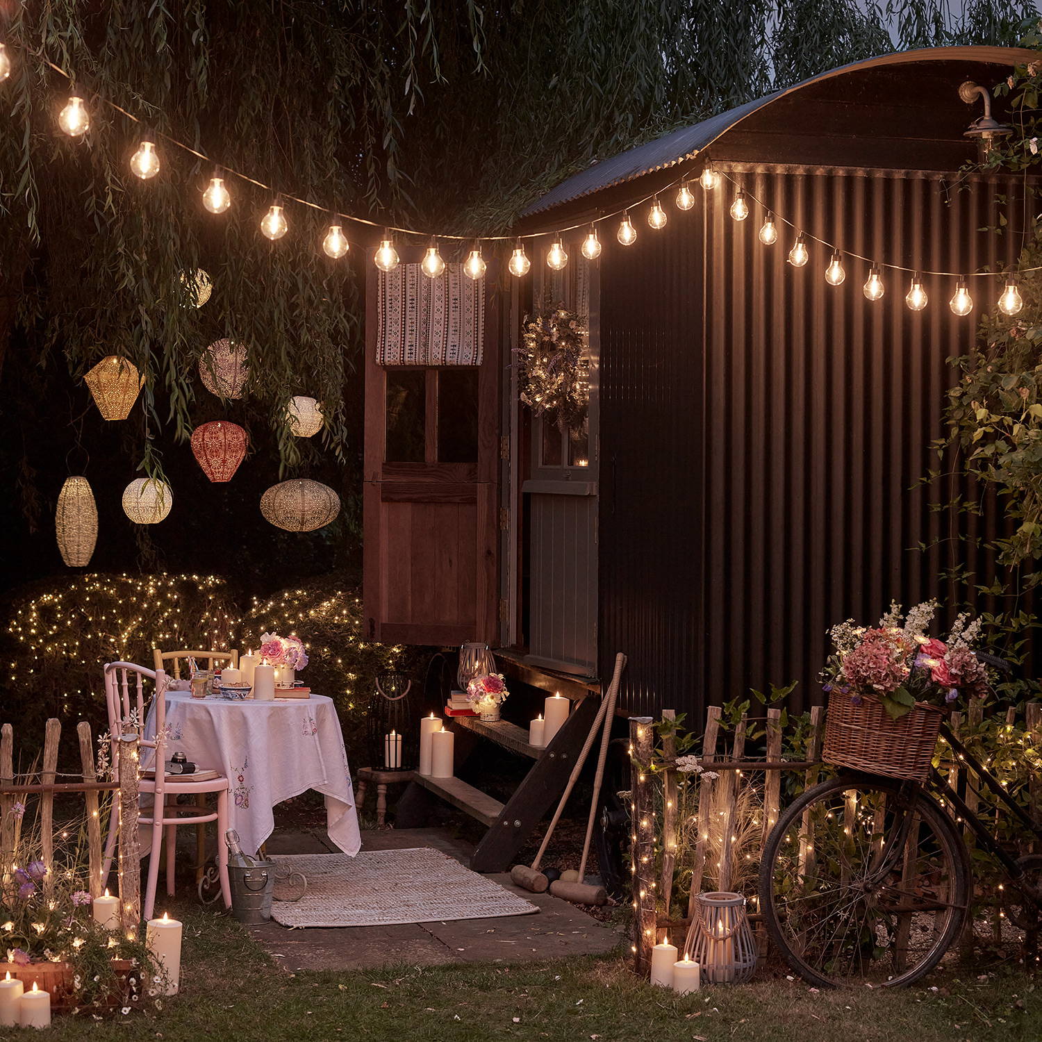 Petit jardin décoré par des lampions, des guirlandes guinguette, des bougie d'extérieur et des filets de jardin. 