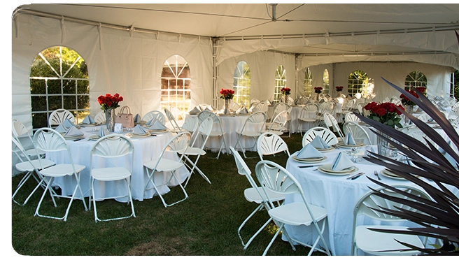 Interior of a tent with round tables, white chairs, and flower centerpieces