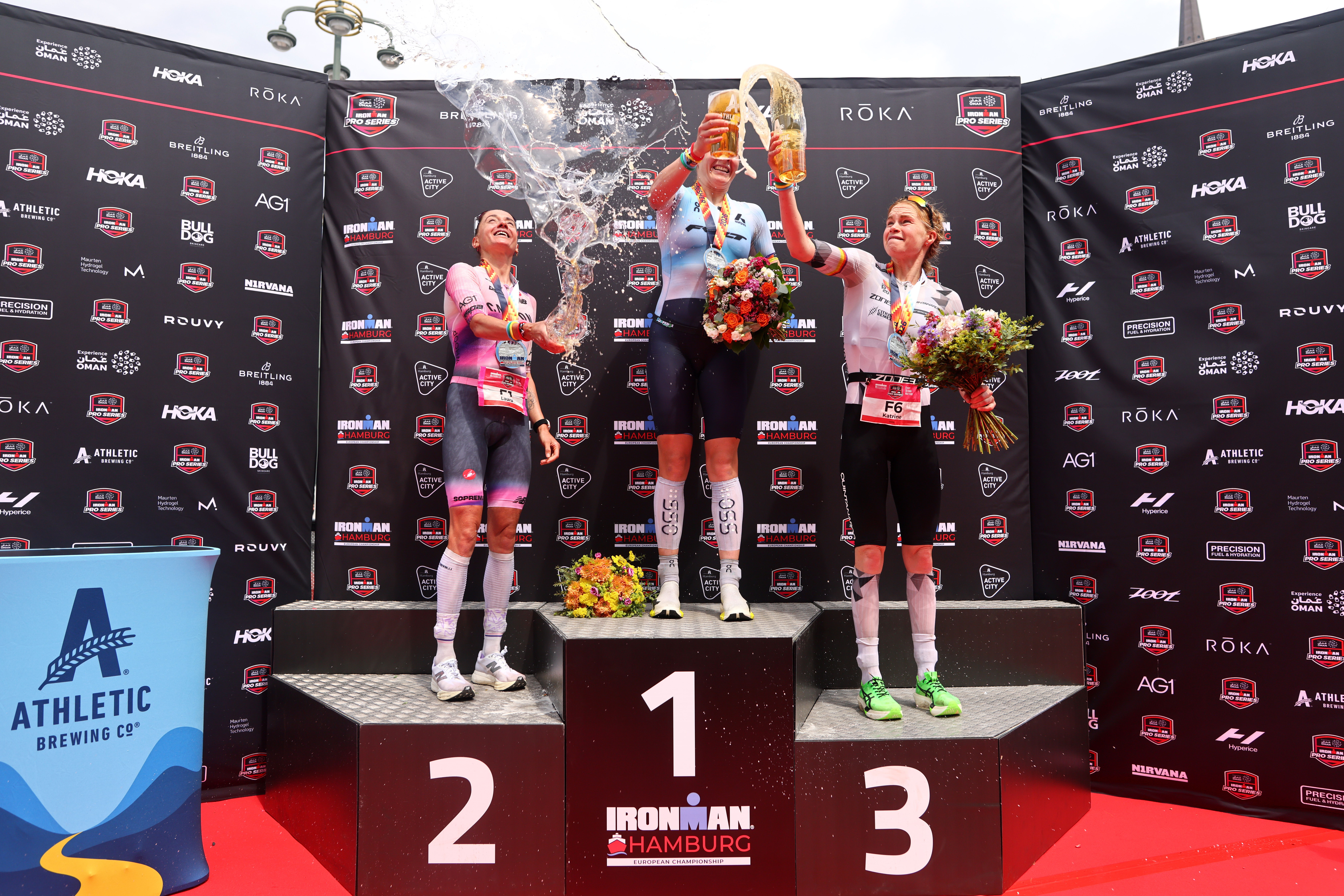Die Silbermedaillengewinnerin Laura Philipp (Deutschland), die Goldmedaillengewinnerin Solveig Løvseth (Norwegen) und die Bronzemedaillengewinnerin Katrine Christensen (Dänemark) feiern auf dem Siegerpodest nach dem Rennen der Profi-Frauen bei der IRONMAN-Europameisterschaft am 7. Juni 2026 in Hamburg.