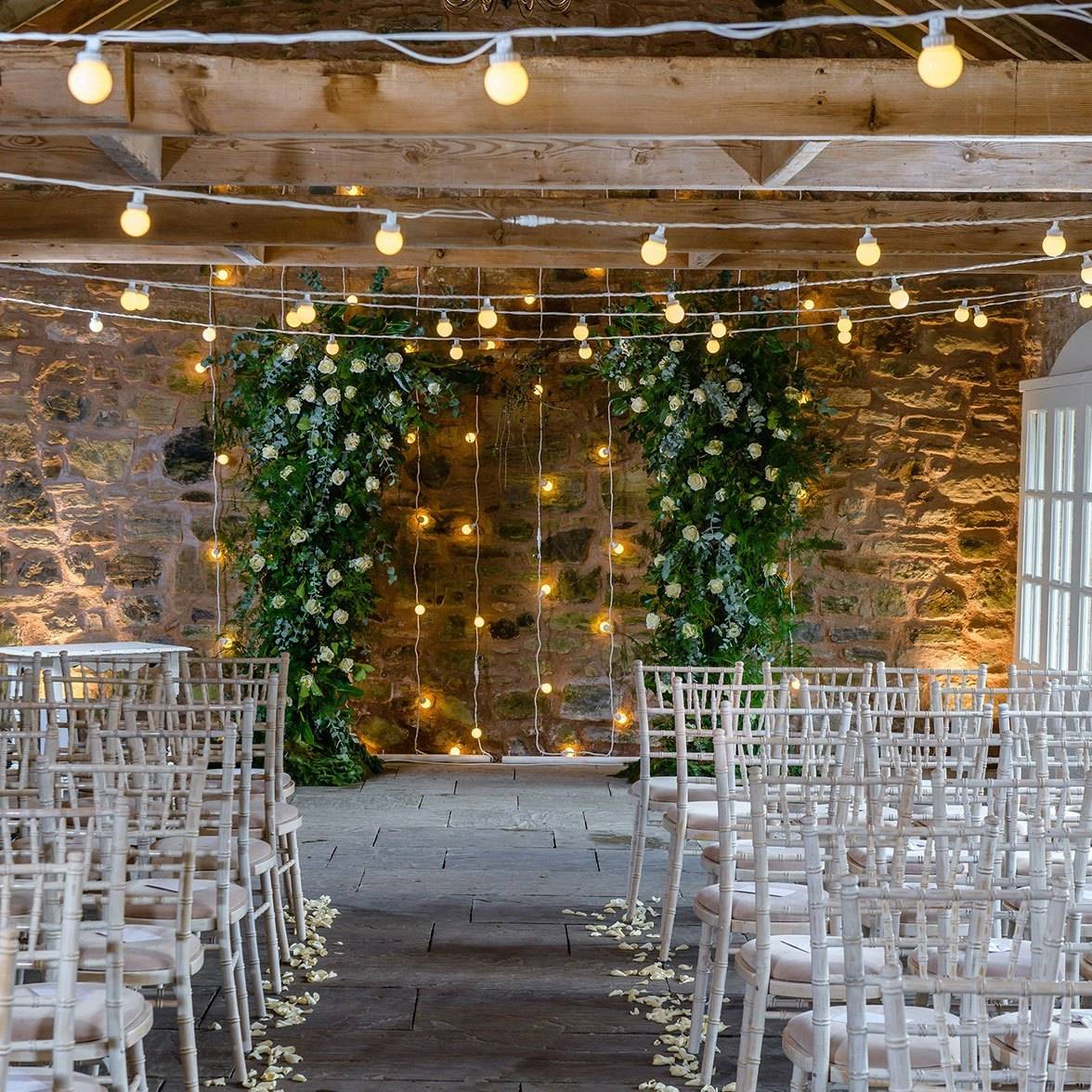 Wedding setting with festoon lights on the ceiling and as a curtain wall.