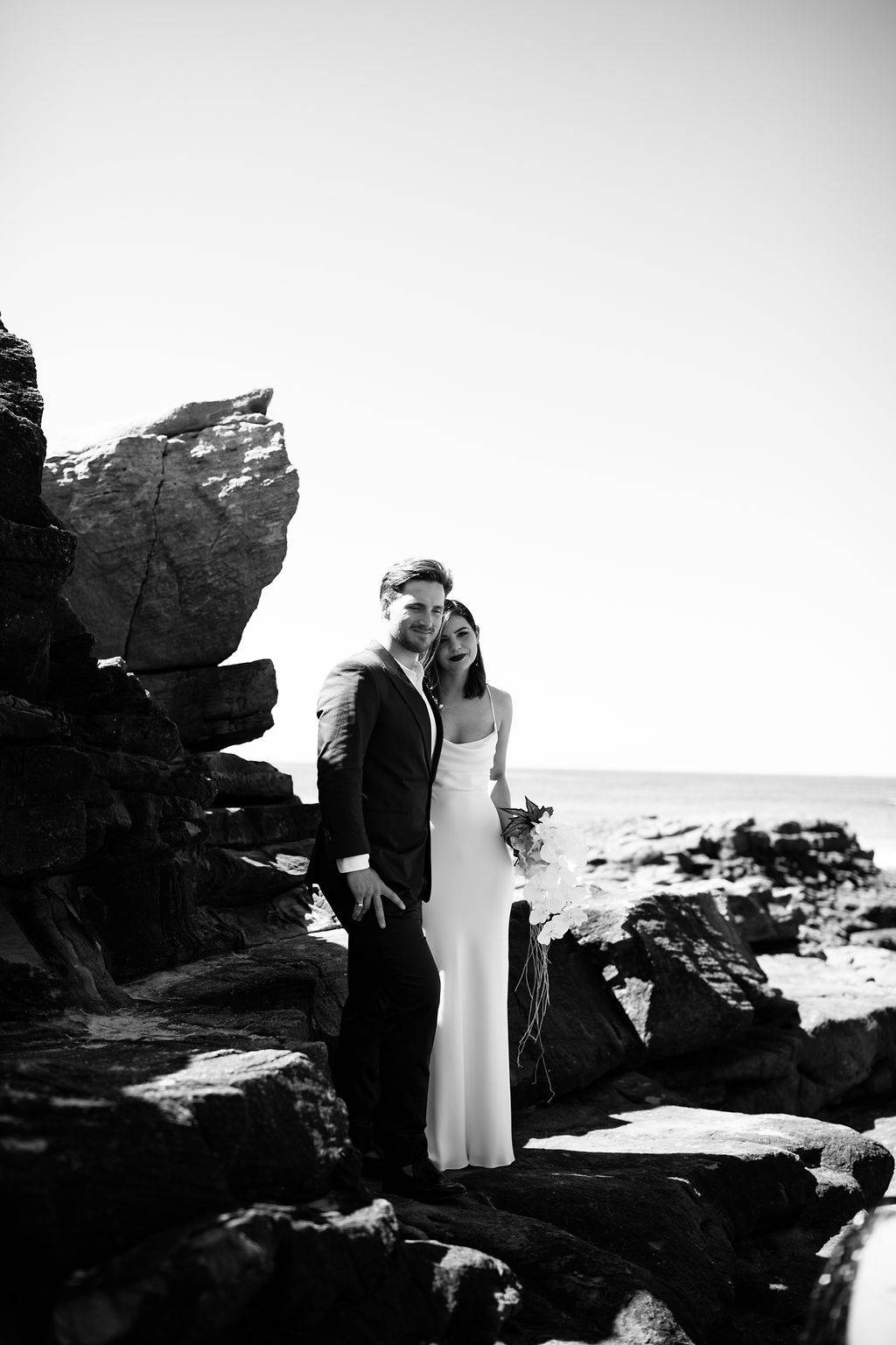 Bride and groom standing on the rocks on the beach