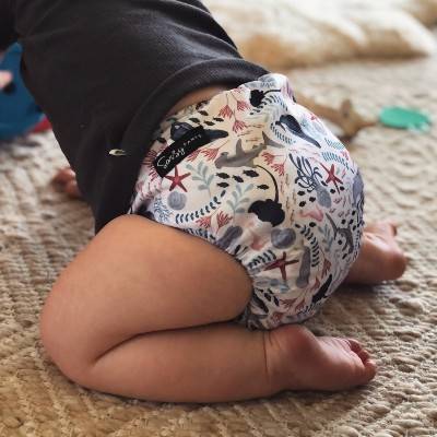 Baby sitting on knees wearing a Sassy Pants reusable cloth nappy - sea shells design