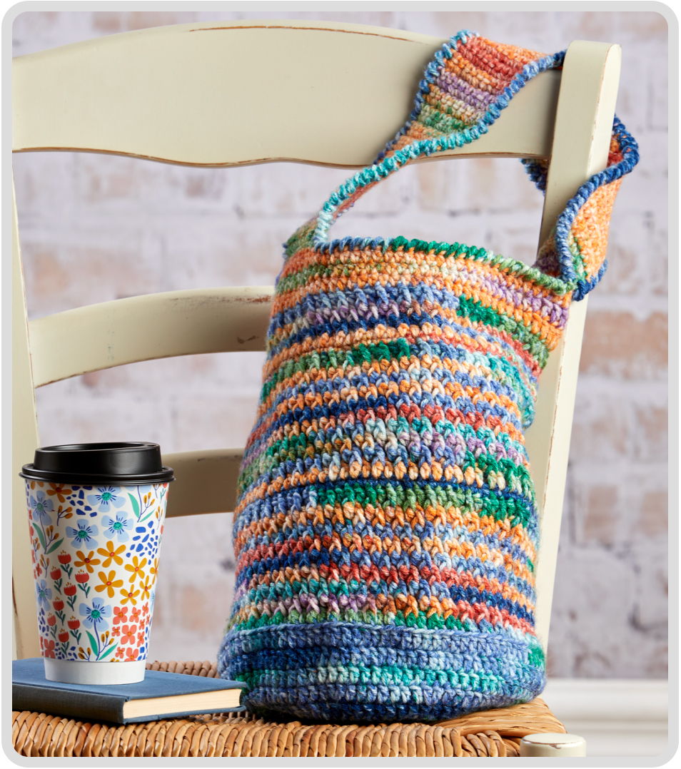 Colorful crochet bag on a chair next to a coffee cup.