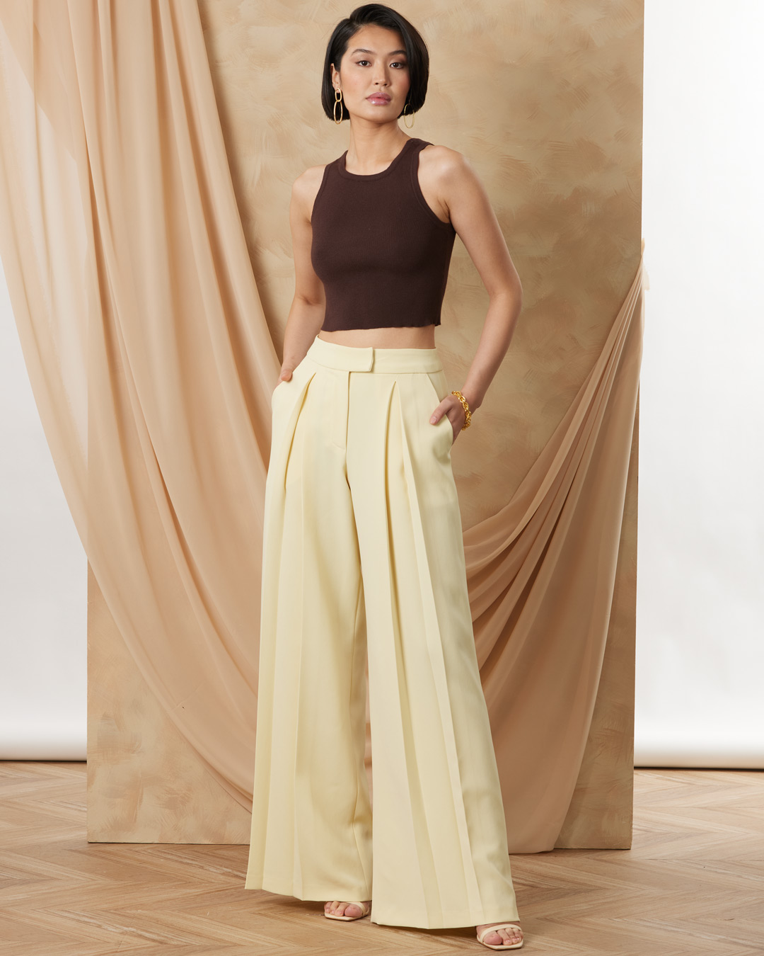 Woman in a yellow outfit poses against a soft, neutral backdrop.