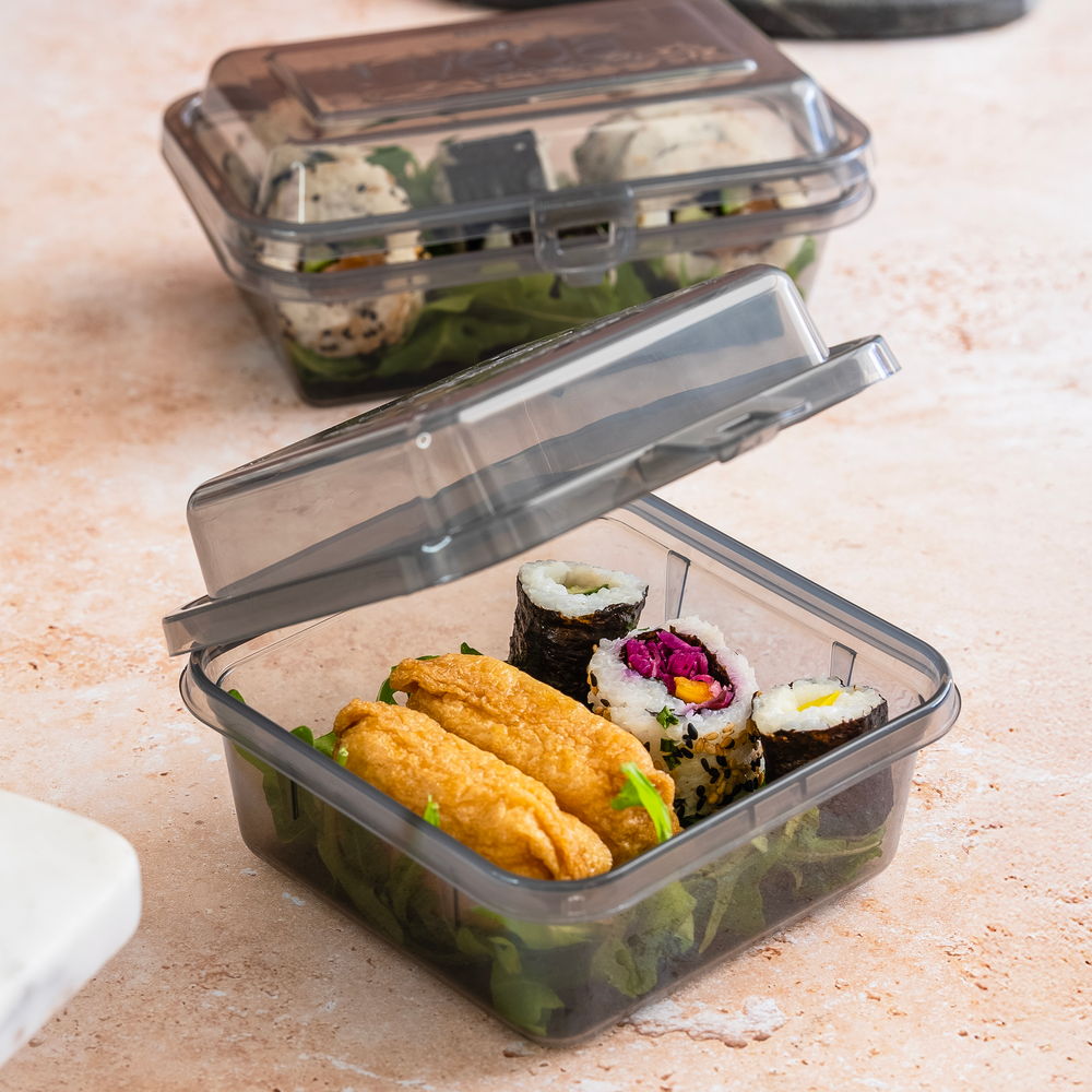 Sushi rolls and inari in a clear plastic container with a lid.
