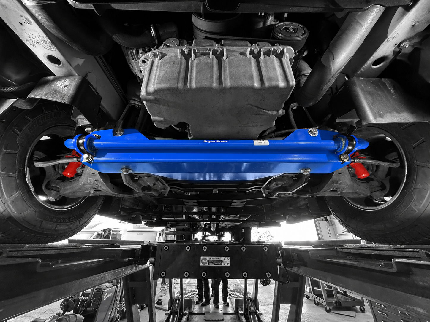 Underneath a car with a blue suspension component and black and white background.