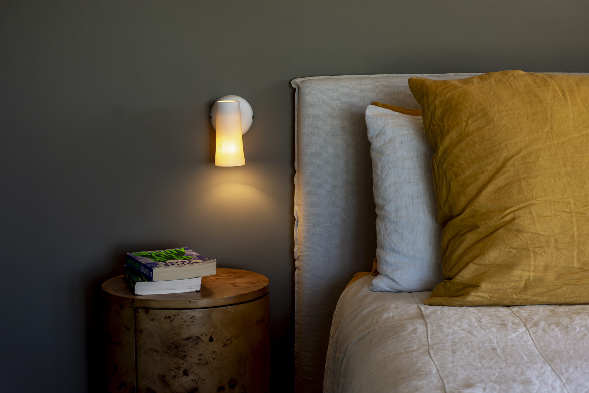 Cosy bedroom corner with a wall lamp above a bedside table
