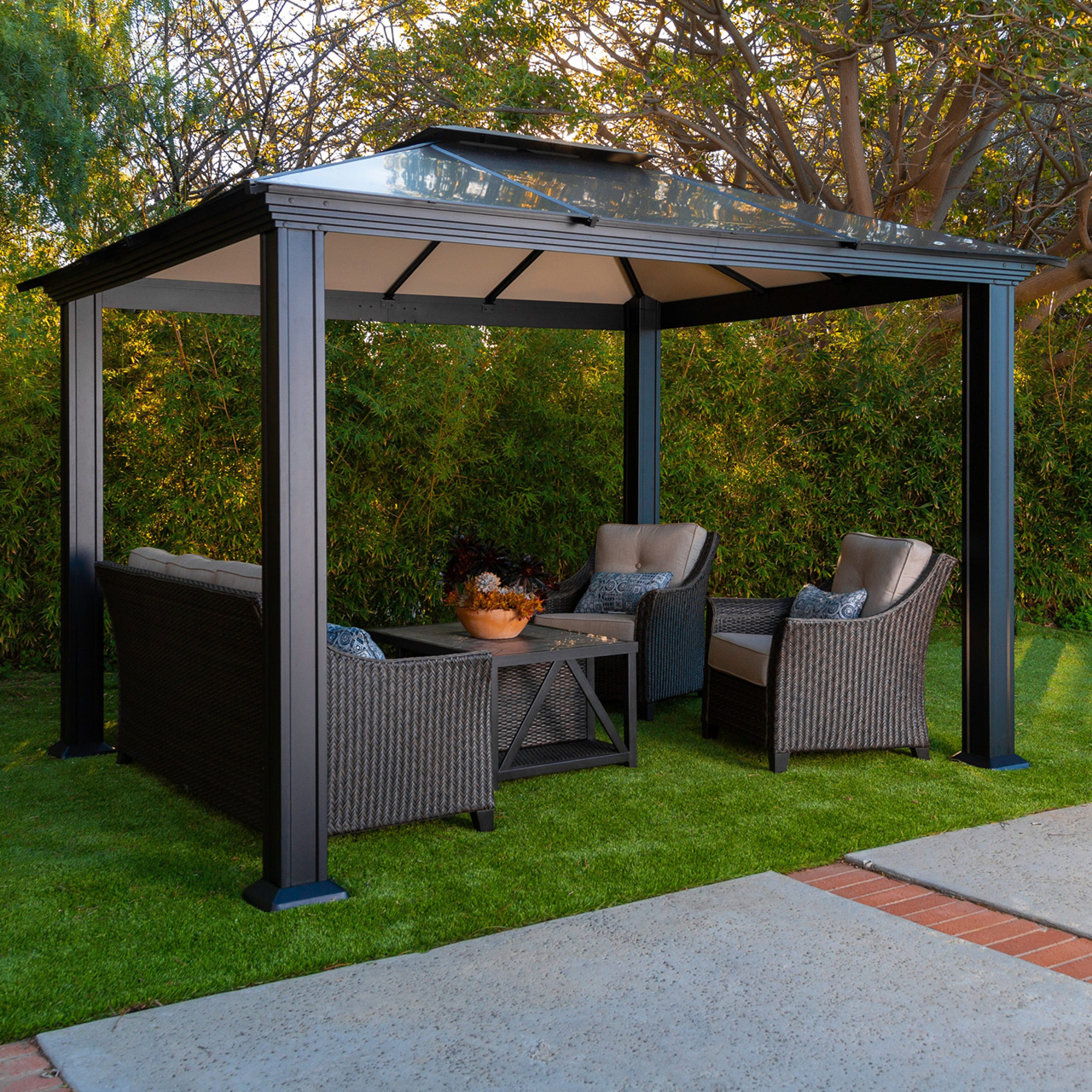 A patio gazebo with seating and a table on green grass.